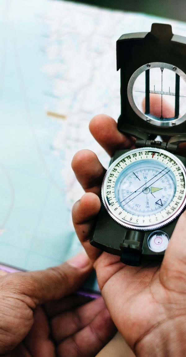 Hand holding compass over a map